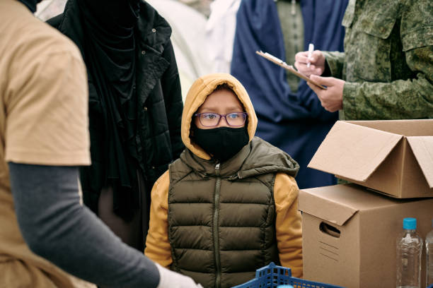 istock Child in protective mask waiting for spreading free food 1347306234