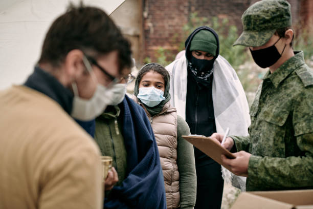 istock Group of migrants in protective masks waiting for donation 1347306250