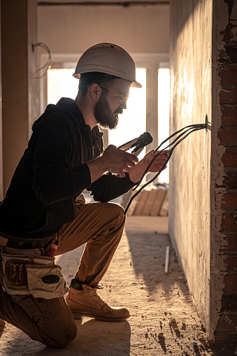 A construction electrician cuts a voltage cable during a repair.