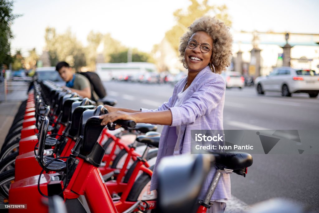 Happy diverse couple of friends renting electric bicycles together Young happy diverse couple of friends exploring the city, renting an electric bicycle and having fun together Electric Bicycle Stock Photo