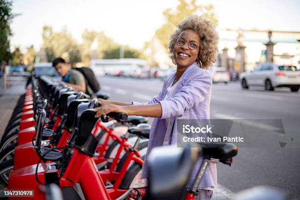 Happy Diverse Couple Of Friends Renting Electric Bicycles Together Stock Photo - Download Image Now