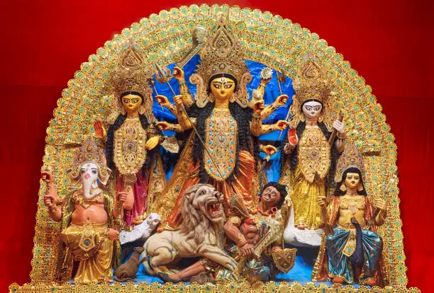 Vibrant looking clay made idol of Hindu Goddess Durga with her family members Goddess Lakshmi (Laxmi), Goddess Saraswati, Lord Ganesha and Kartikeya inside a puja pandal during Durga puja festival 2021 happening in Kolkata. Goddess Durga is seen slaying buffalo demon Mahishasura (Asura).