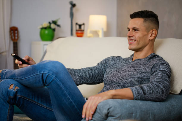 istock Young man relaxing on the sofa and watching TV 1347313749