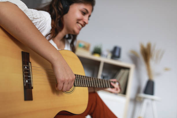 istock Cheerful young woman having fun playing acoustic guitar 1347314122