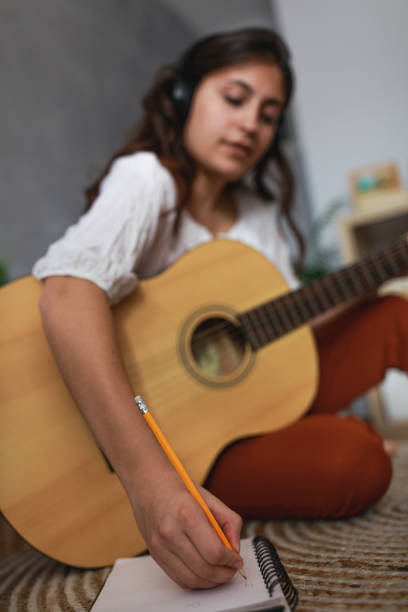 istock Young woman writing chords for a song she is composing 1347314128