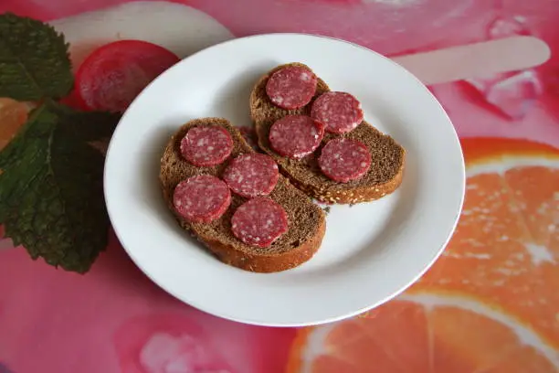 Photo of Two black bread sandwiches with salami