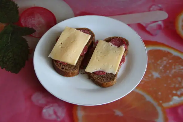 Photo of Two black bread sandwiches with salami and cheese