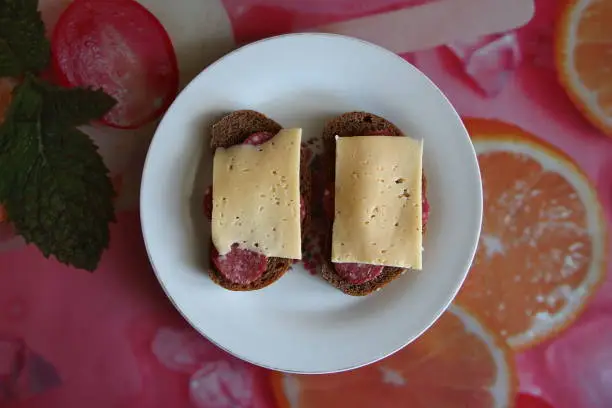 Photo of Two black bread sandwiches with salami and cheese, top view