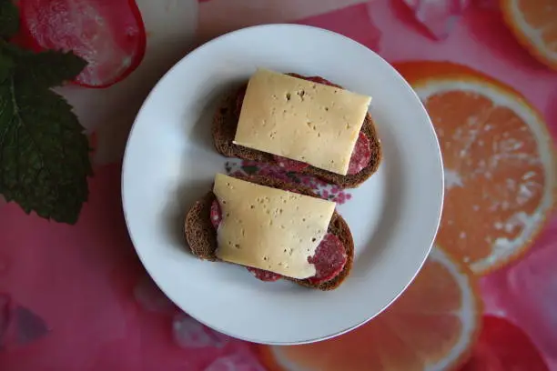 Photo of Two black bread sandwiches with salami and cheese, top view