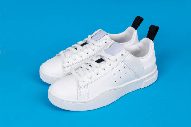 istock Pair of new white sneakers on blue background 1347316427