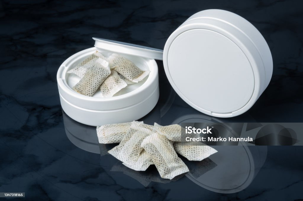 Closeup of a white swedish snus can and portion snuff pouches. Helsinki / Finland - OCTOBER 18, 2021: Closeup of a white swedish snus can and portion snuff pouches. Snuff Box Stock Photo