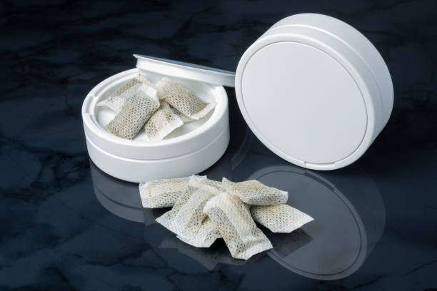 Closeup of a white swedish snus can and portion snuff pouches. stock photo