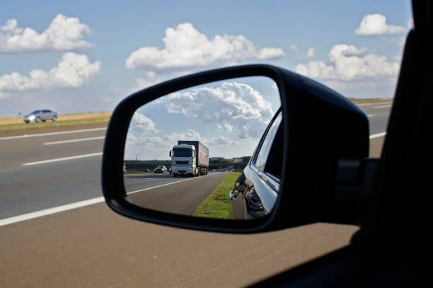 lkw auf einer autobahn im rückspiegel an einem sommertag gesehen. - rear view mirror car mirror rear view stock-fotos und bilder