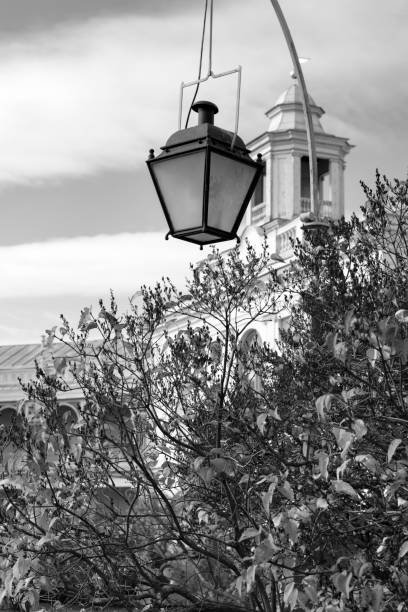 An old lantern above the trees against the background of an old castle tower and a cloudy sky. Black and white image. stock photo