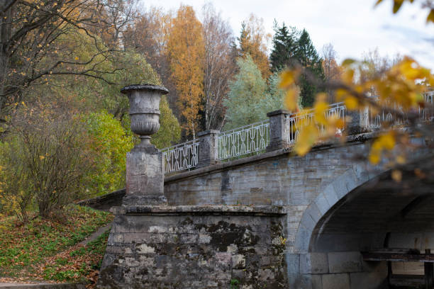 Autumn landscape, flowerpot and part of an old bridge in the park against the background of colored yellowed trees. stock photo