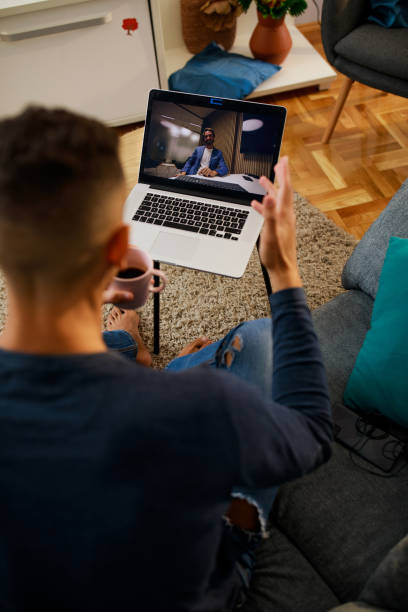 istock Young man having coffee and video conferencing a friend 1347323896