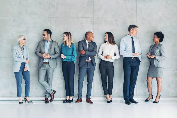 Mixed large group of business persons standing against a wall
