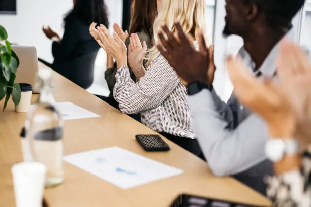 Photo of Close-up of co-workers clapping at a meeting.