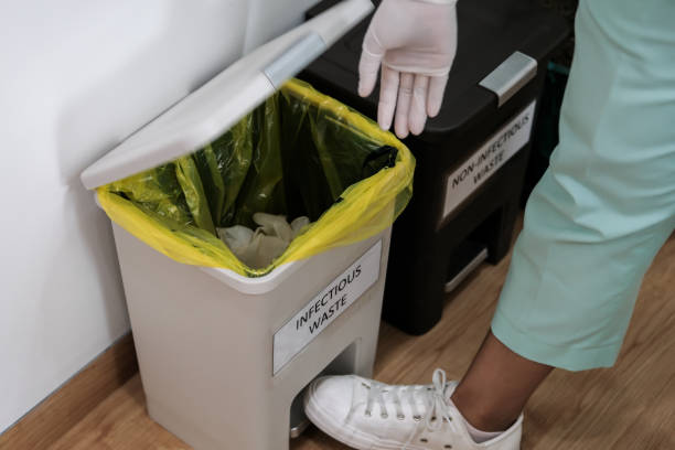 hospital worker discarding infectious medical waste into disposal container bin. close up of biohazard contaminated clinical waste - bio hazard imagens e fotografias de stock