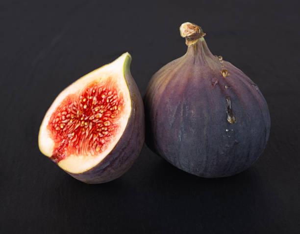 istock Fresh delicious young whole figs and fig halves on a beautiful black background 1347326835
