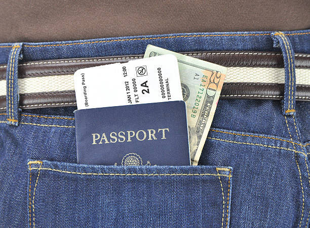 Airline Boarding Pasassport and Twenty Dollar Bill Currency American passport with airline boarding pass and U.S.A. twenty dollar bill currency in rear pocket of denim blue jeans jeans denim passport pocket stock pictures, royalty-free photos & images