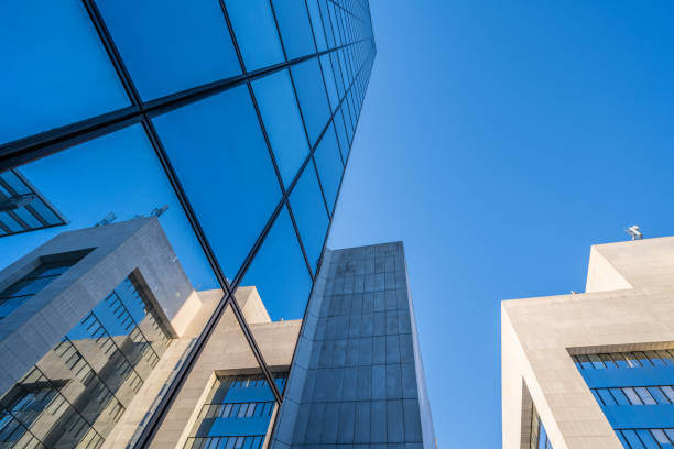 istock Looking up at glass and marble buildings with reflections 1347328950