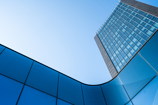 Curvy glass architectural element with reflections and a skyscraper in the upper right corner.