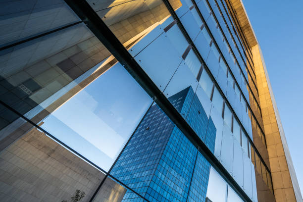 istock Looking up at glass and marble buildings with reflections 1347329010