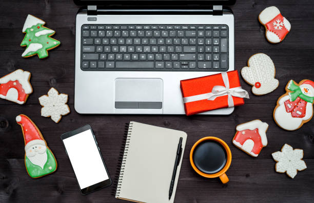 istock Laptop computer, blank notebook, Christmas present, cup of coffee and  gingerbread cookies on dark wood background, copy space. Top view, flat lay. 1347331263