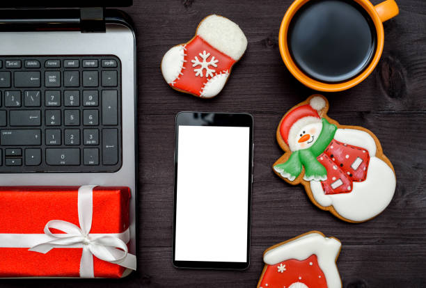 istock Laptop computer, smartphone with blank screen, Christmas present, cup of coffee and  gingerbread cookies on dark wood background, copy space. Top view, flat lay. 1347331270