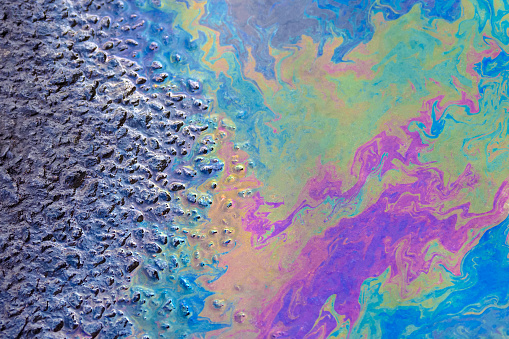 Iridescent stains of gasoline, top view. Oil stain on asphalt, color gasoline fuel spots on asphalt road as texture or background. environmental pollution concept