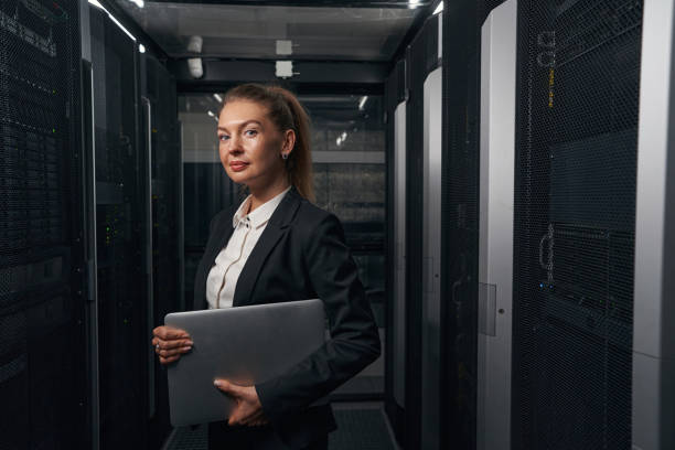 istock Confident businesswoman with laptop computer in data center 1347338256