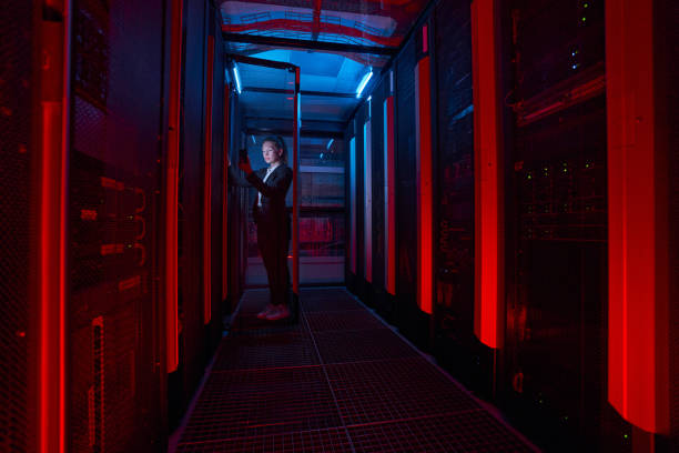 istock Female technician working on phone with servers in data center 1347338365