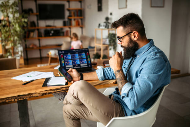 Cryptocurrency investor trading at home using his laptop Mid adult handsome man working at home using laptop, while his daughter doing her homework in background in living room cryptocurrency stock pictures, royalty-free photos & images