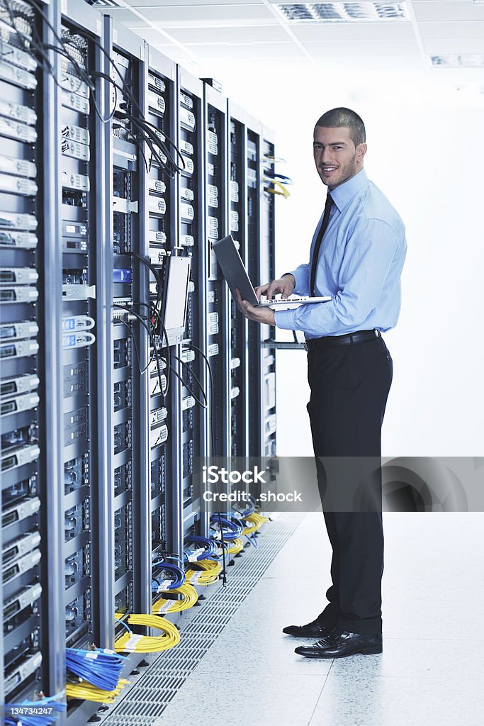 Hombre de negocios con ordenador portátil en la sala de servidores de red - Foto de stock de Sala de servidores libre de derechos