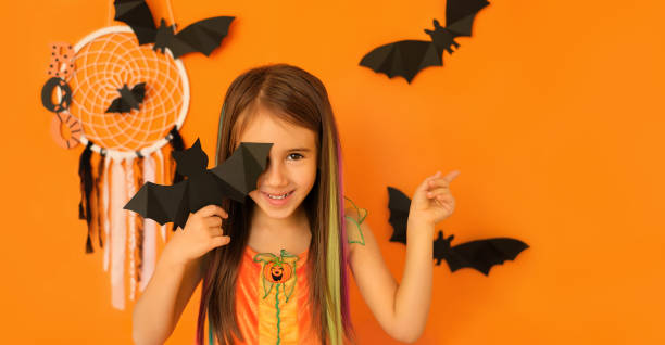 istock The girl on an orange studio Halloween background. 1347346385