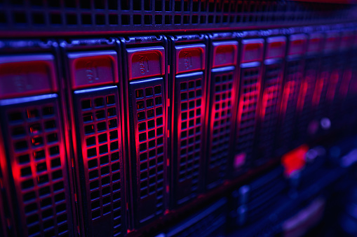 Closeup of LED-illuminated network server rack panel with several hard disk drives