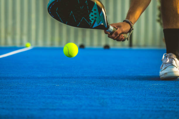 un giovane giocatore di paddle tennis che prende la palla con la racchetta - sportivo che gioca a padel - padel foto e immagini stock