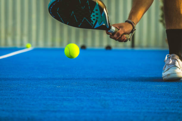 a young paddle tennis player catching the ball with the racket - sportsman playing padel game - the paddle racket imagens e fotografias de stock