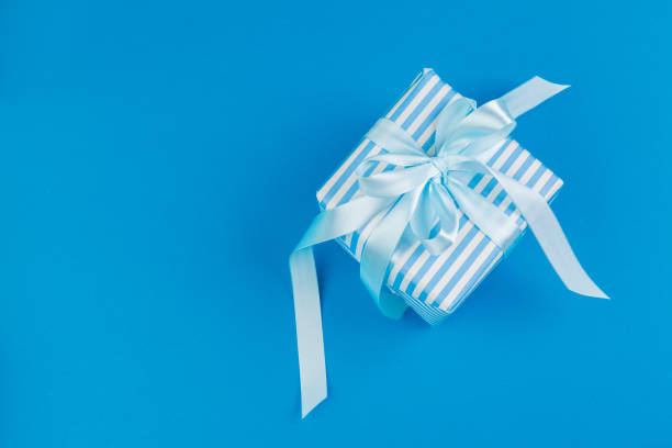 istock Flat lay of gift box decorated with bow on blue background 1347358869