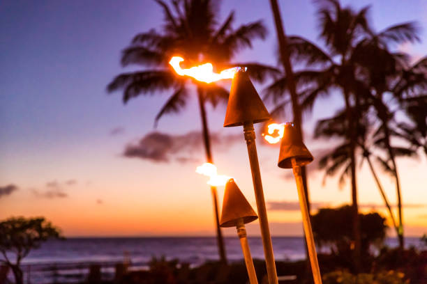 hawaii sunset with fire torches. hawaiian icon, lights burning at dusk at beach resort or restaurants for outdoor lighting and decoration, cozy atmosphere. - hawaï eilanden stockfoto's en -beelden