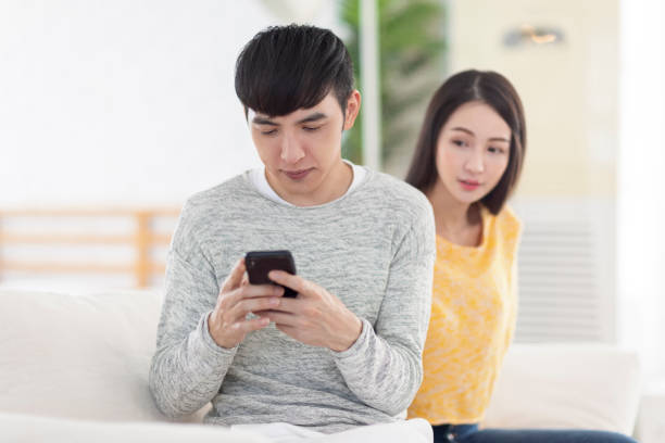 istock Young man using smartphone.Young woman peeks at man's smartphone screen. 1347365211