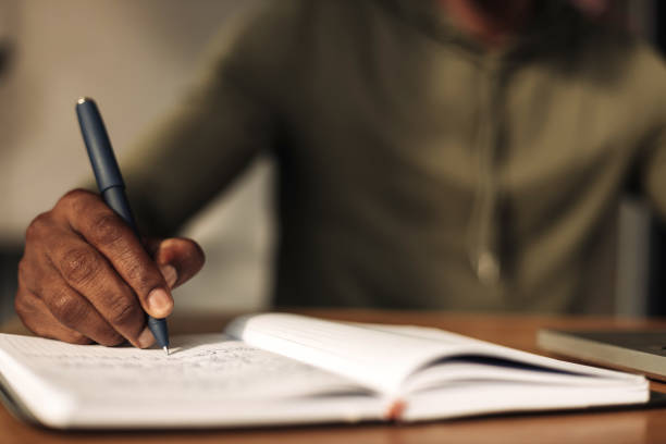istock close-up of a hand writes in a notebook with a notepad at the table. a man writes with a pen in a notebook 1347367858
