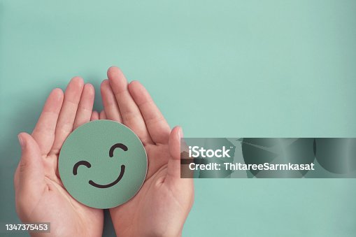istock Hands holding green happy smile face paper cut, good feedback rating and positive customer review, experience, satisfaction survey ,mental health assessment, child wellness,world mental health day concept 1347375453