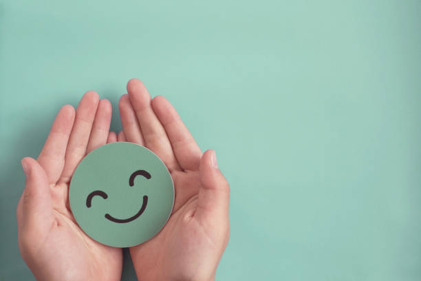 hands holding green happy smile face paper cut, good feedback rating and positive customer review, experience, satisfaction survey ,mental health assessment, child wellness,world mental health day concept - mental health imagens e fotografias de stock