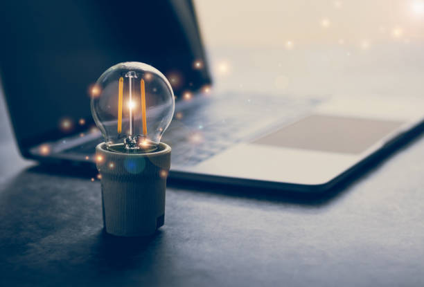 istock Bright lamp or glowing light bulb with laptop or computer 1347379264