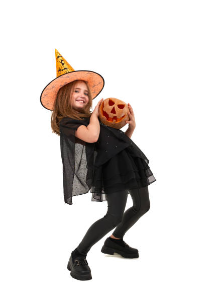 Joyful girl in witch costume holds pumpkin stock photo