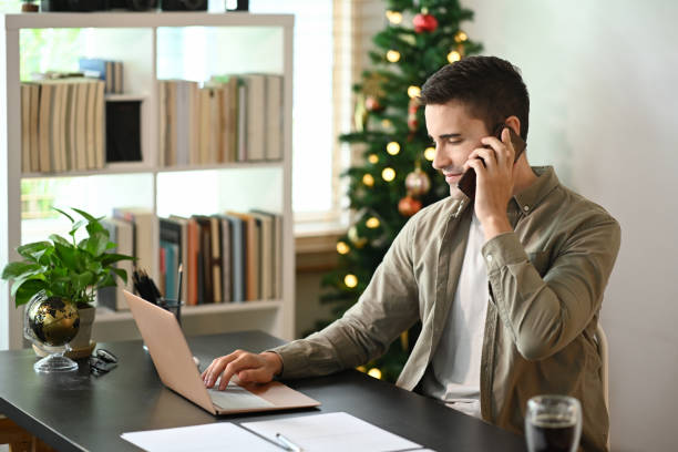 istock Man working with laptop computer and talking on mobile phone at home. 1347409492