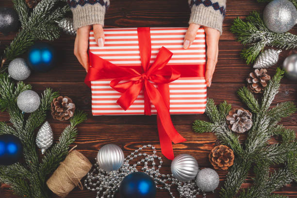 istock Christmas decorations on wooden table with decorated gift in woman's hands 1347412334