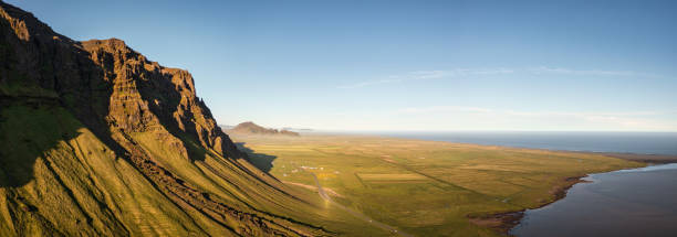 Sudurland Iceland South Coast Sunset XXL Panorama. Stiched aerial drone point of view panorama along the south coast mountain range and north atlantic ocean of Sudurland in South Central Iceland. Warm Sunset light over country road Route 1 along coastal mountain range between Selfoss and Vik, South Central Iceland, Iceland, Nordic Countries, Europe